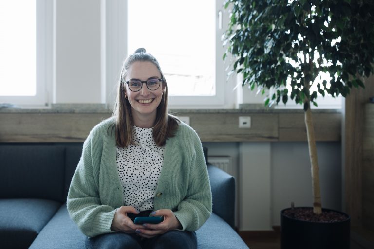 Xenia Kalkmann hält ein Handy und lächelt