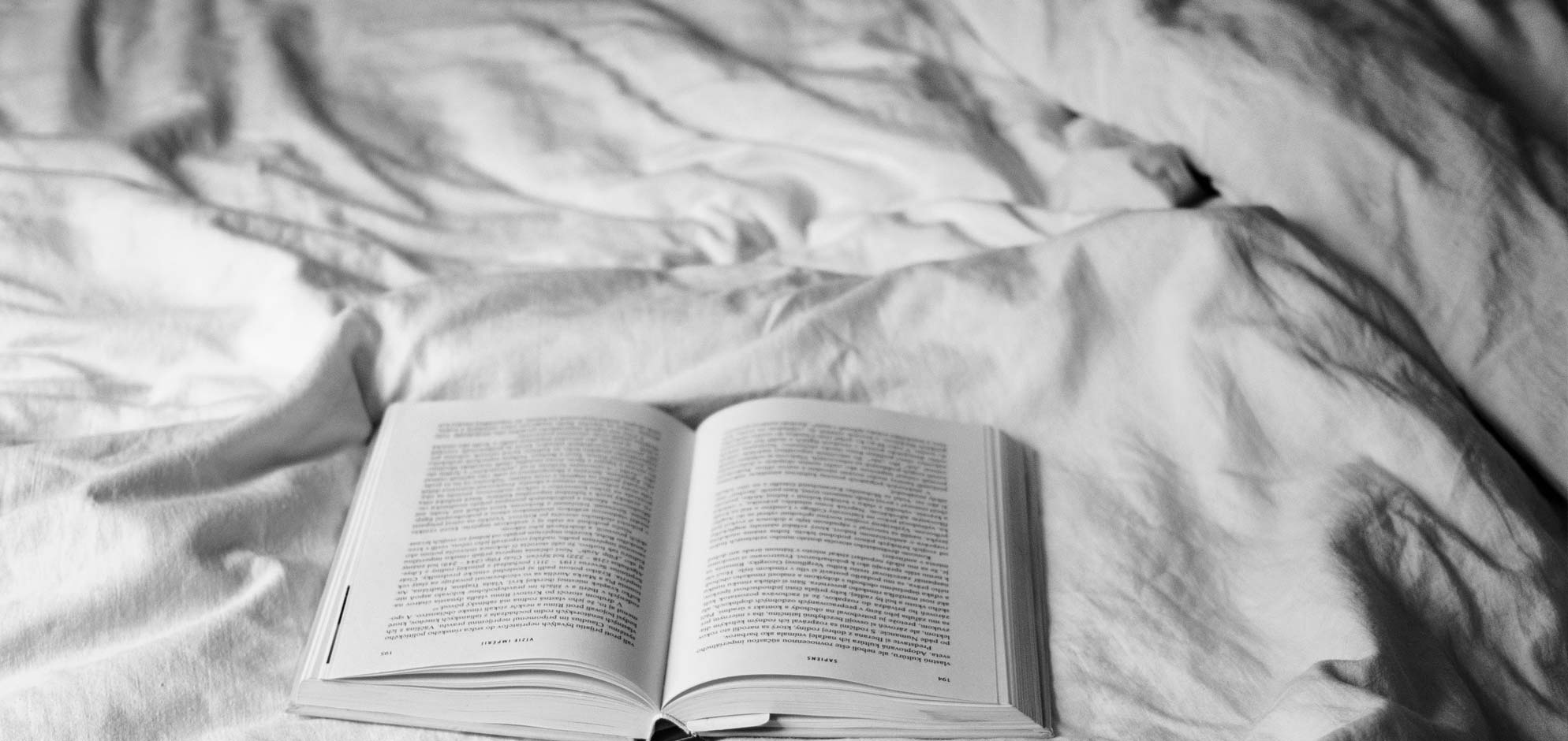 Ein Buch liegt auf einer weißen Bettdecke