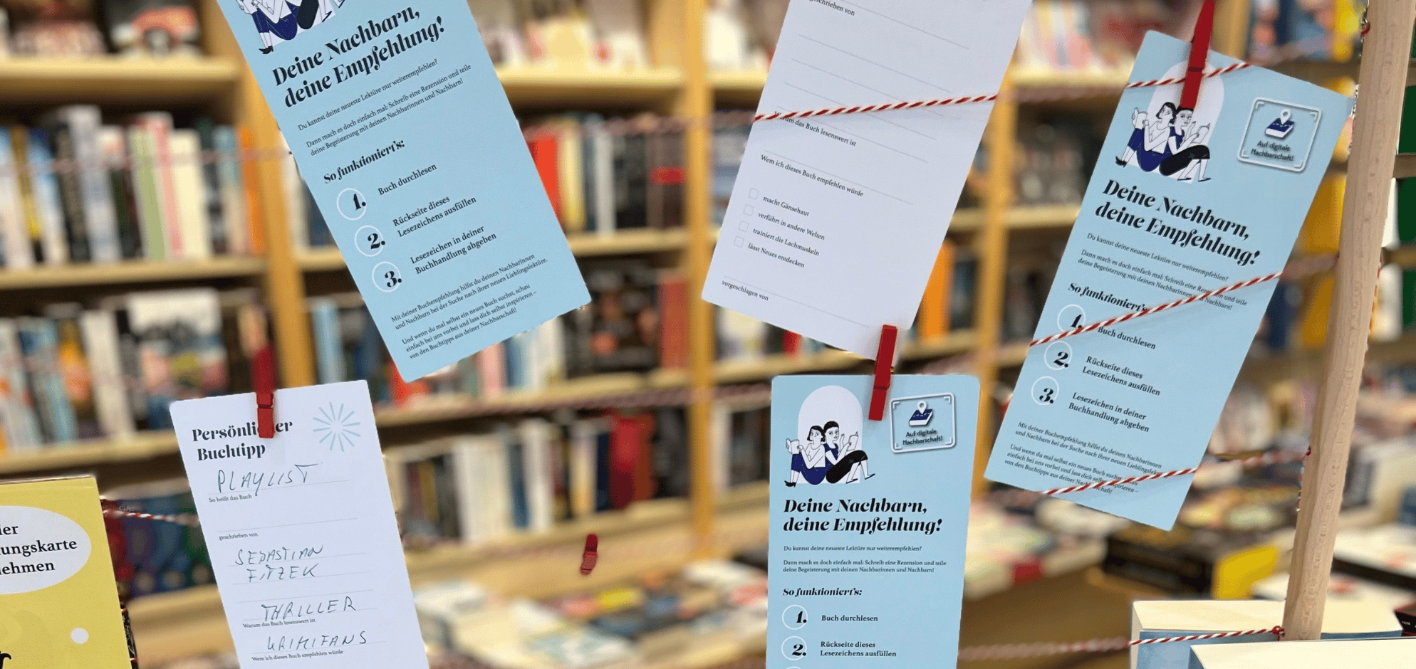 In einer Buchhandlung hängen an einer Wäscheleine Leseempfehlungen auf Karten.