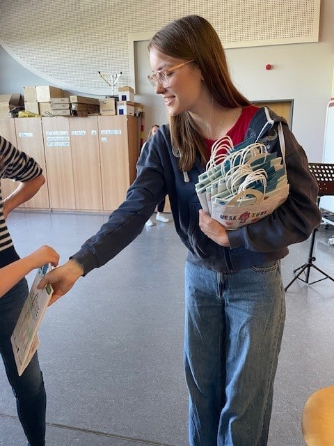 Die Auszubildende der Buchhandlung Ruthmann verteilt die Lesetüten an Erstklässler*innen.